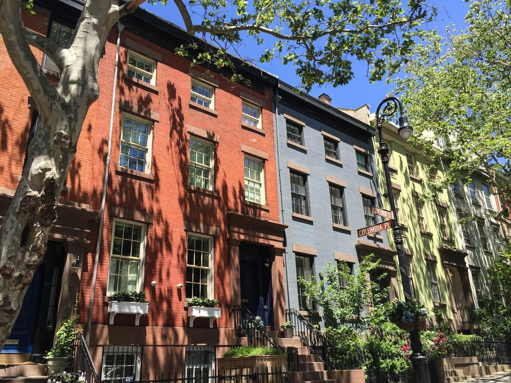 Brick rowhouses with front steps along a tree-lined city street
